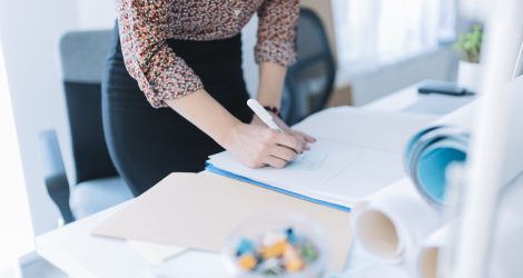 close-up-businesswoman-writing-adhesive-note-office(1)